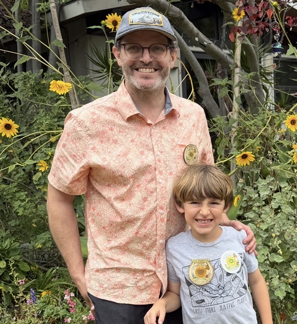 Marcus and his son Luca smiling together among flowering garden plants